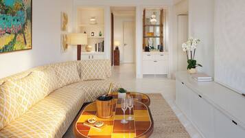 Una sala moderna con un sofá estampado, una mesa de centro con comida y bebidas, y vista al área de la cocina.