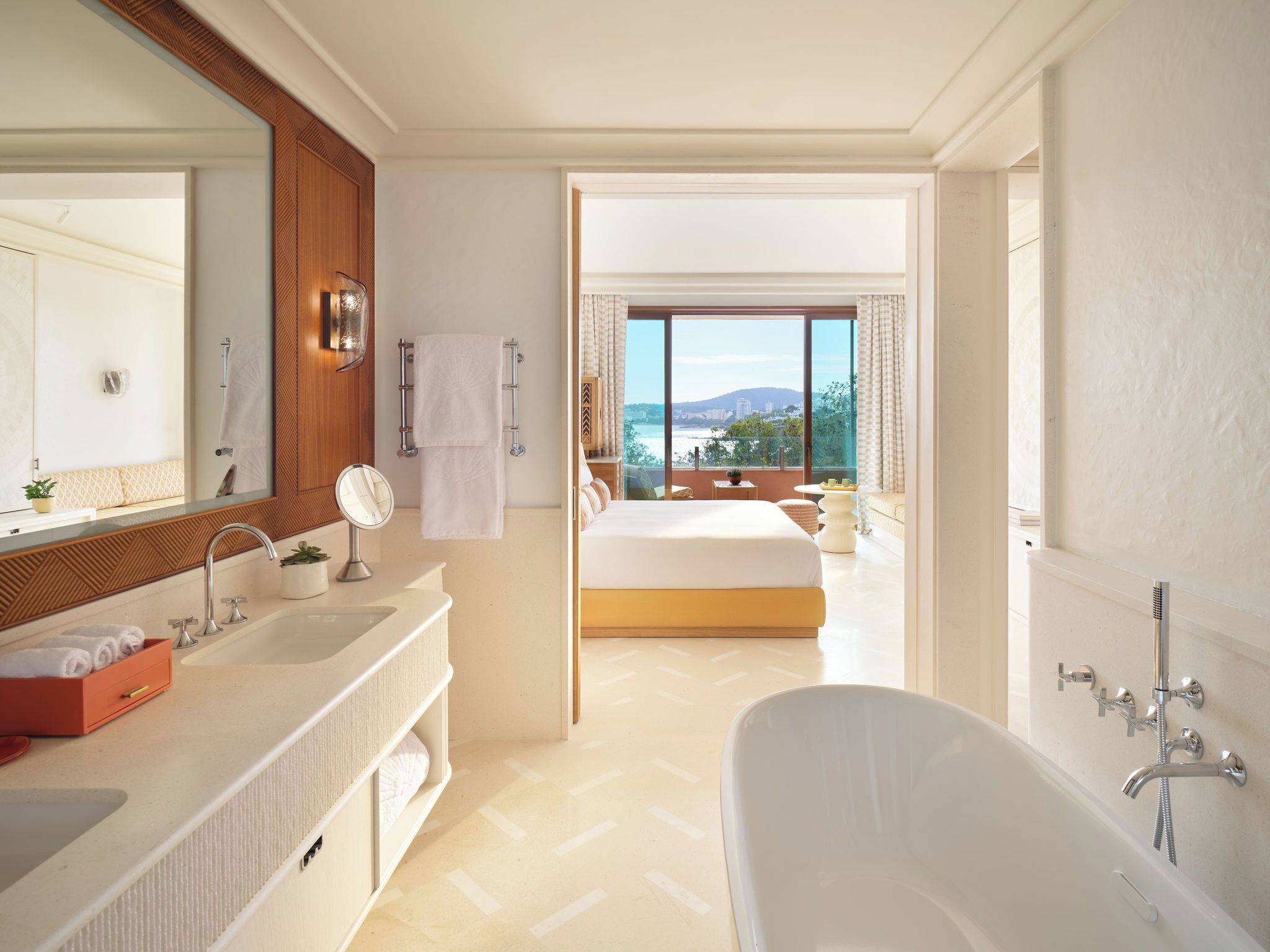 A modern bathroom with a bathtub, a large mirror, and a vanity with a sink.