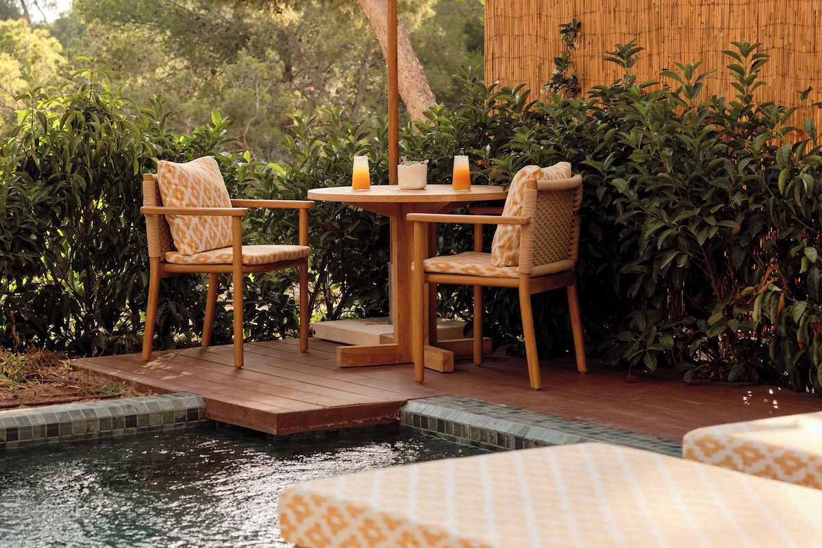 Un espace aménagé au bord de la piscine, avec une table et des chaises, un parasol et un mur en bambou.