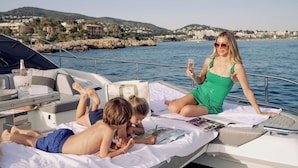 A boat with a white deck, a bottle of champagne, and a person holding a glass. - Mandarin Oriental Punta Negra, Mallorca (Calvia)