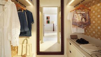 A hallway with clothing racks, a mirror, and a view into another room.