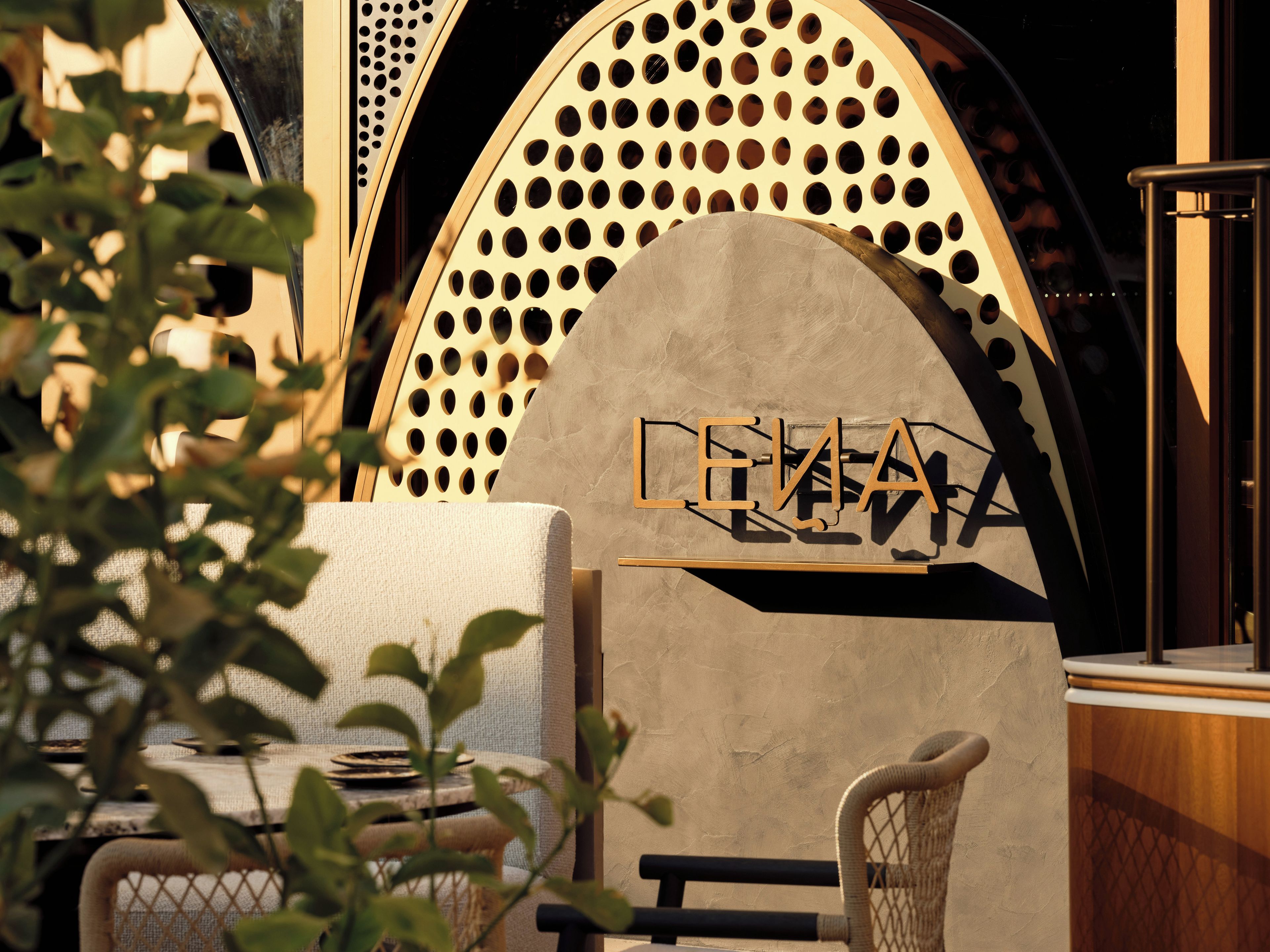 A modern interior with a large arched wall, a seating area, and a sign with the word 'LEINHA'.