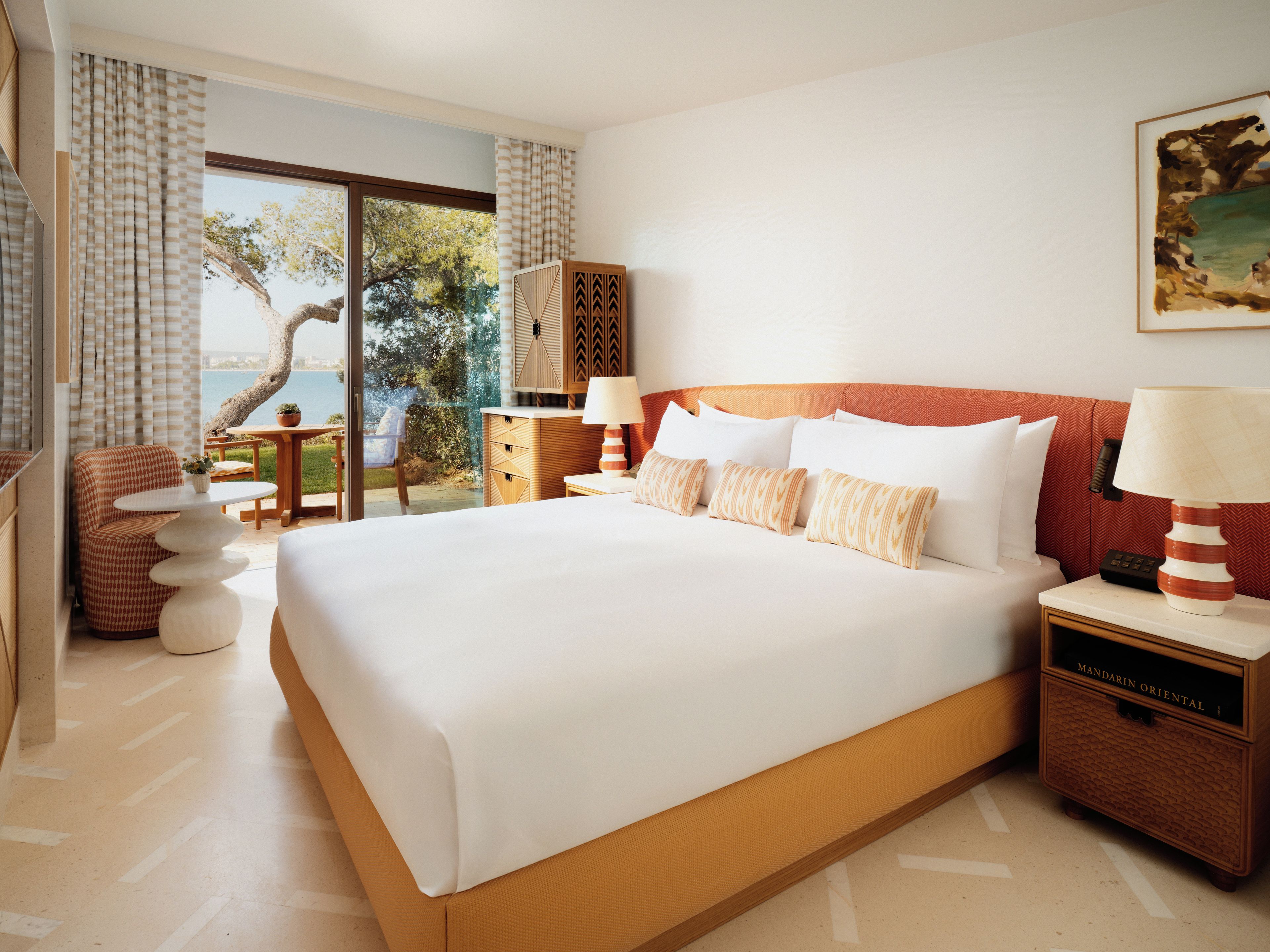 Une chambre d’hôtel avec un grand lit, un bureau, une chaise, une petite table et une vue sur l’extérieur.
