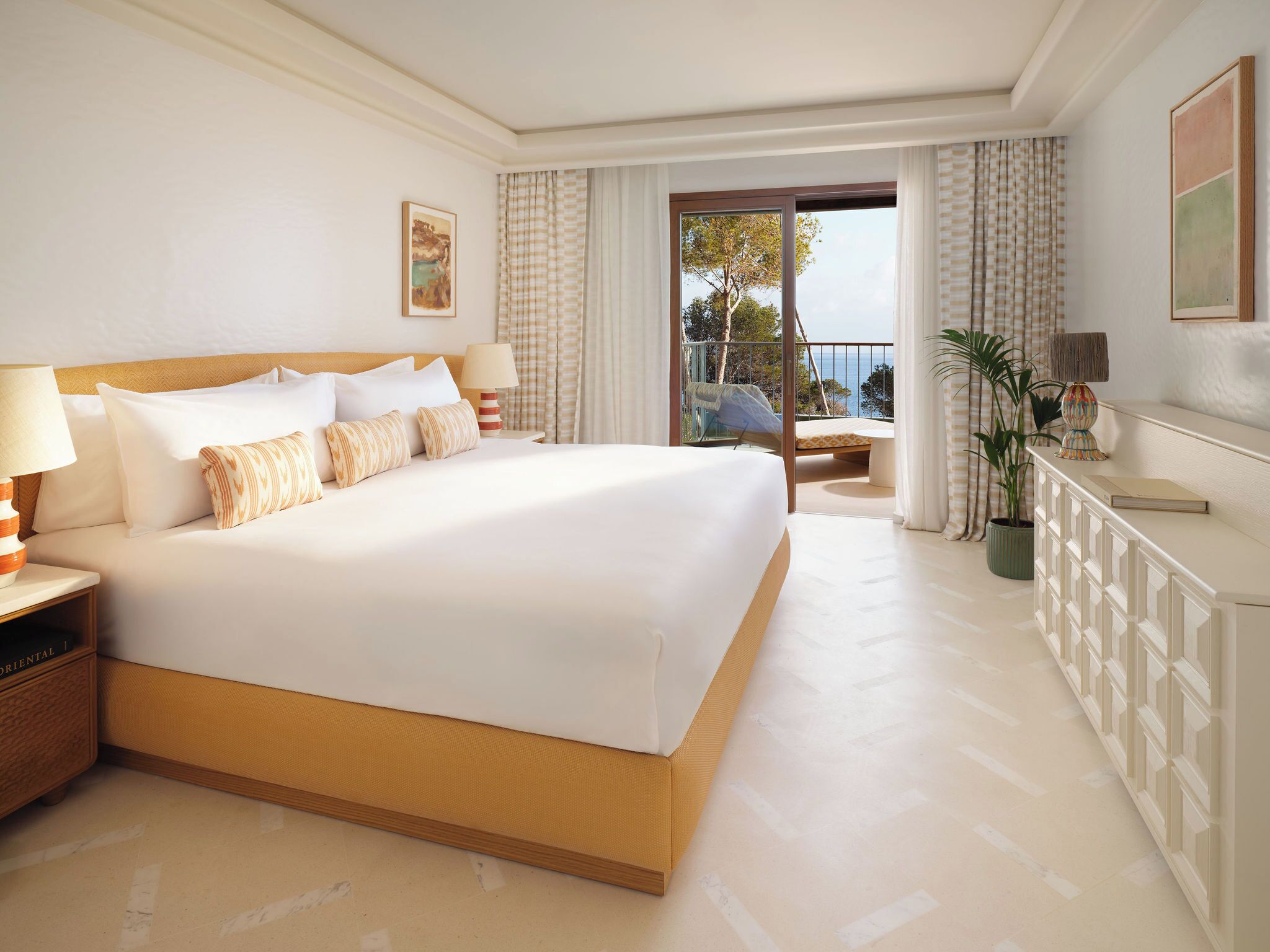A hotel room with a large bed, a nightstand, a desk, a chair, and a view of the outdoors.