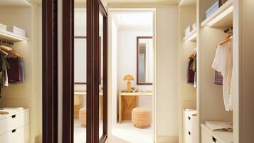 A hallway with a wooden door frame, a vanity with a mirror, and a bed in the background.