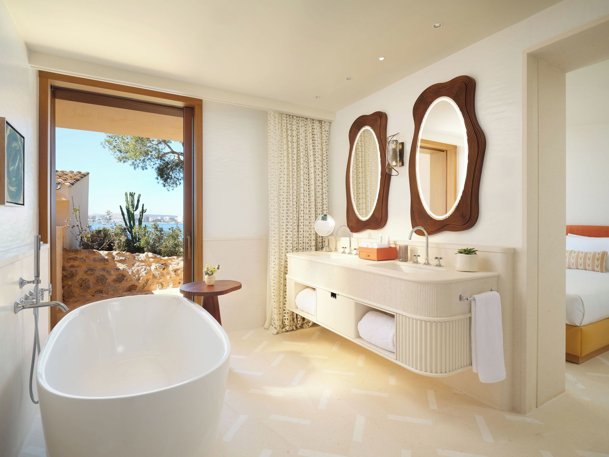 Un baño moderno con una bañera independiente, un tocador con espejo y vistas al exterior.