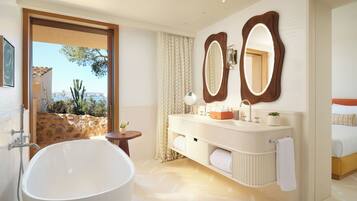A modern bathroom with a freestanding bathtub, a vanity with a mirror, and a view of the outdoors.