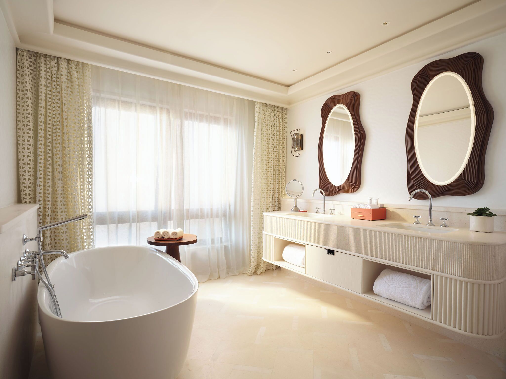 Un baño moderno con una bañera independiente, un tocador con espejo y una mesita con toallas.