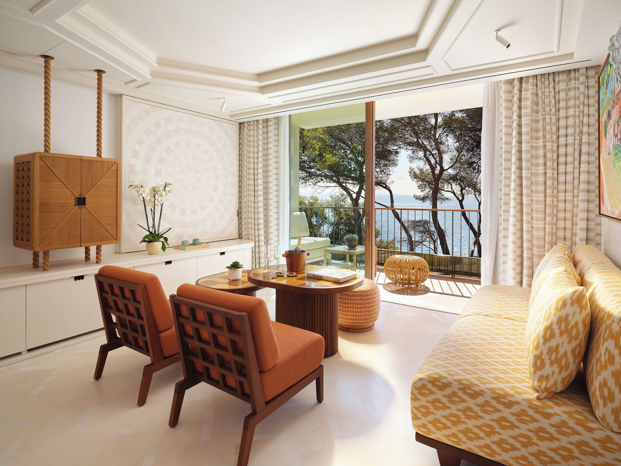 Una sala de estar moderna con un sofá, sillas, una mesa de comedor y vista al mar.