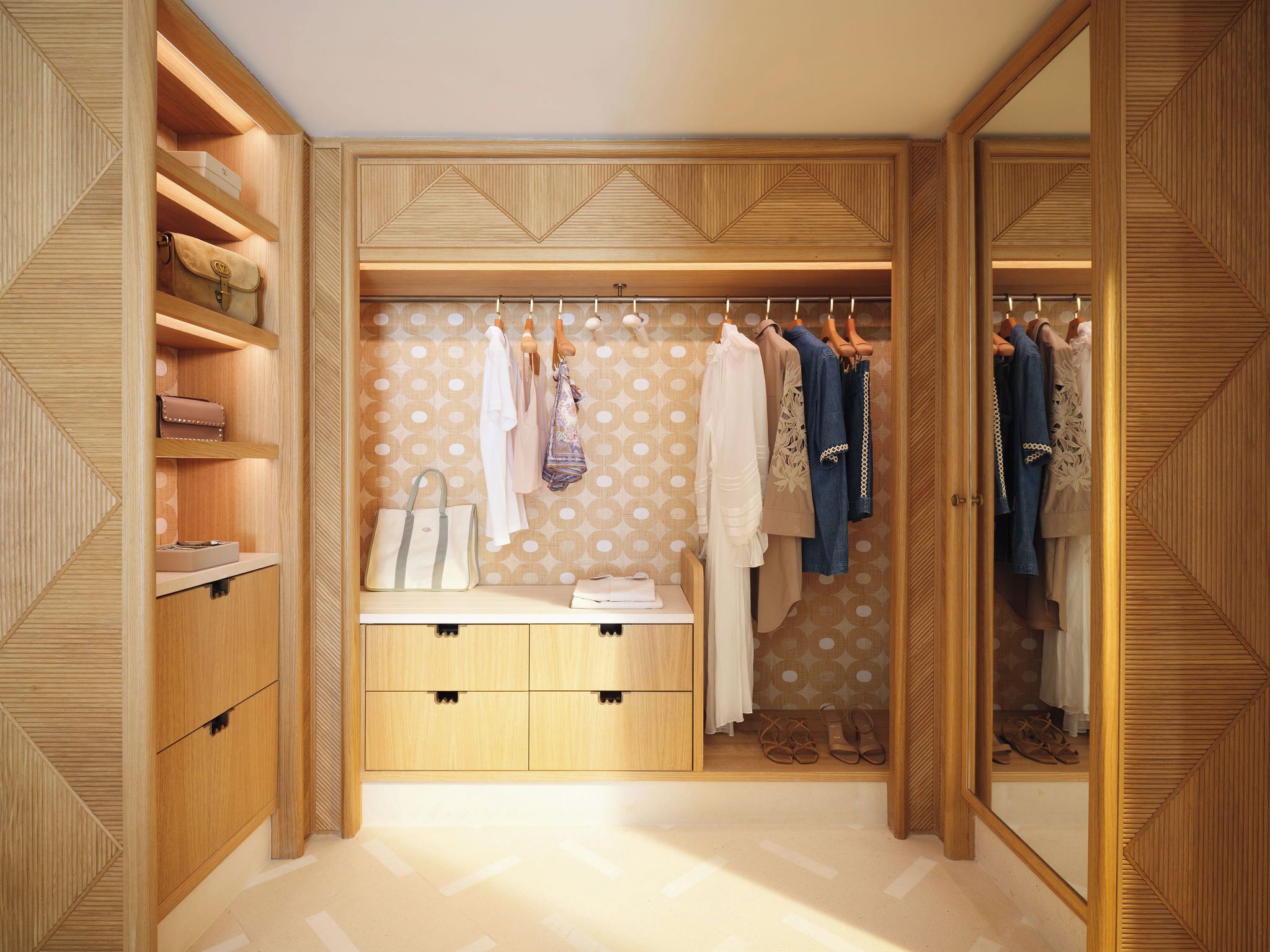 Un dressing avec des meubles en bois, des vêtements suspendus et un espace coiffeuse.