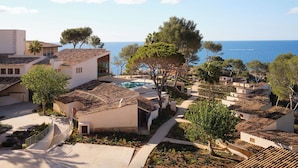 Un complejo turístico frente al mar con arquitectura mediterránea, una piscina y vistas al océano.