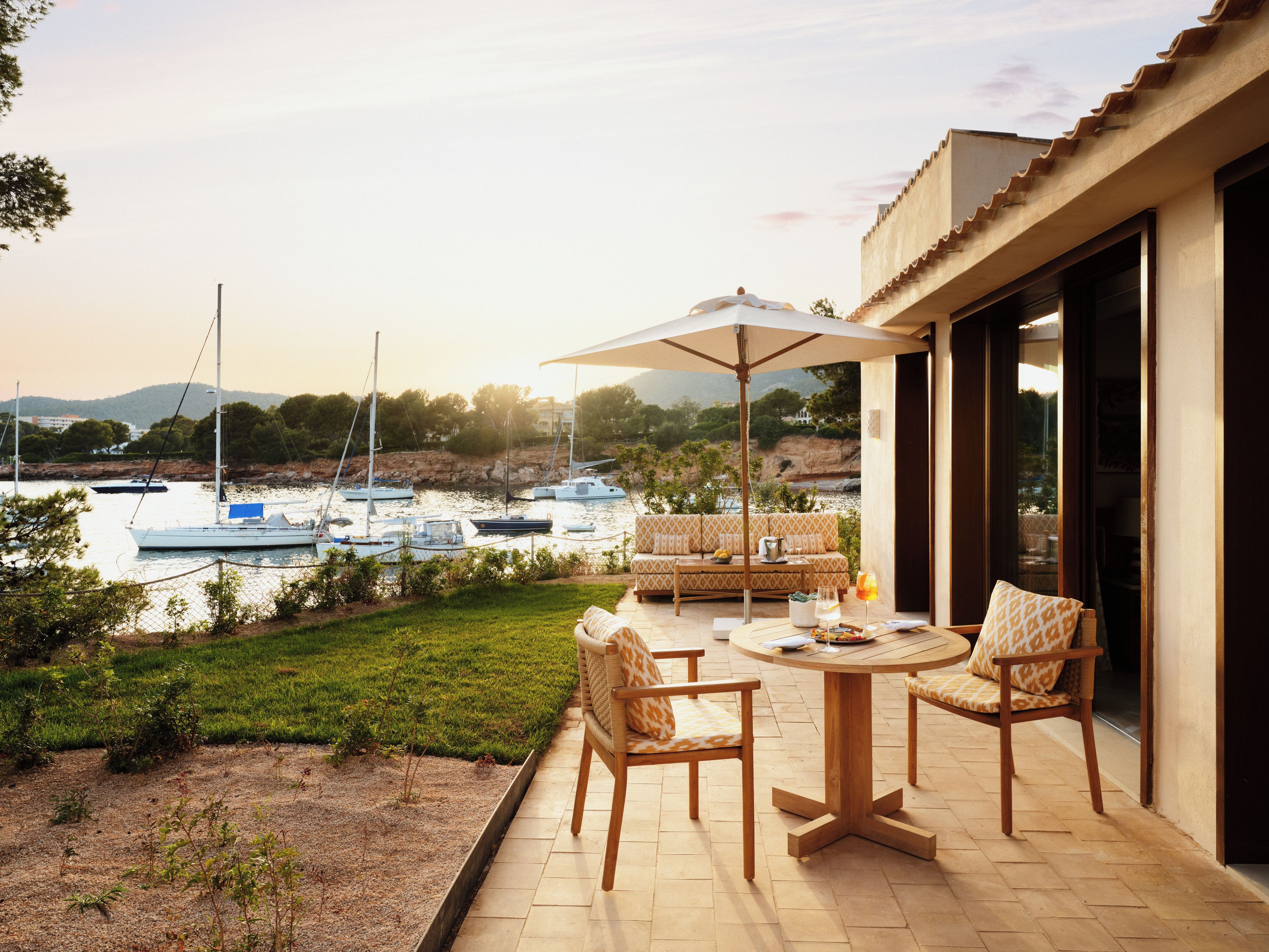 Un patio al aire libre con una mesa y sillas, con vista a un puerto deportivo lleno de barcos.