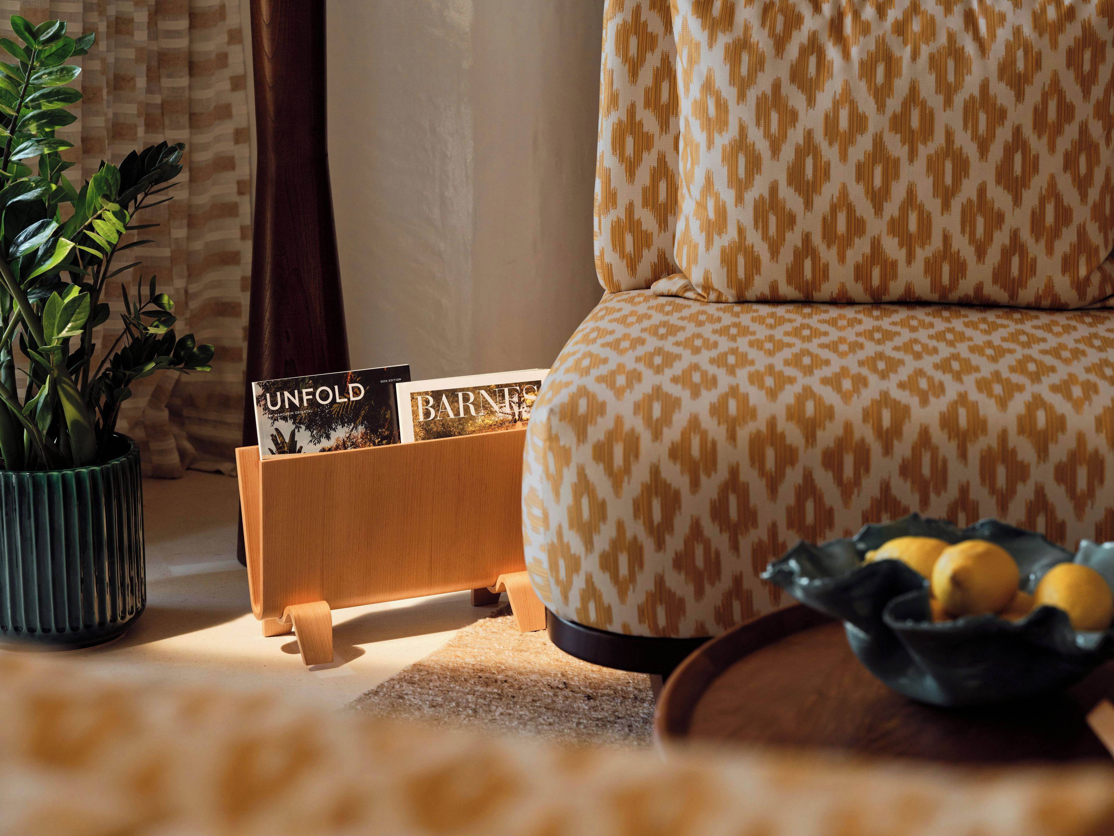 Un salon chaleureux avec un canapé à motifs, une petite table en bois sur laquelle sont posés des magazines, une plante en pot et un bol de citrons.