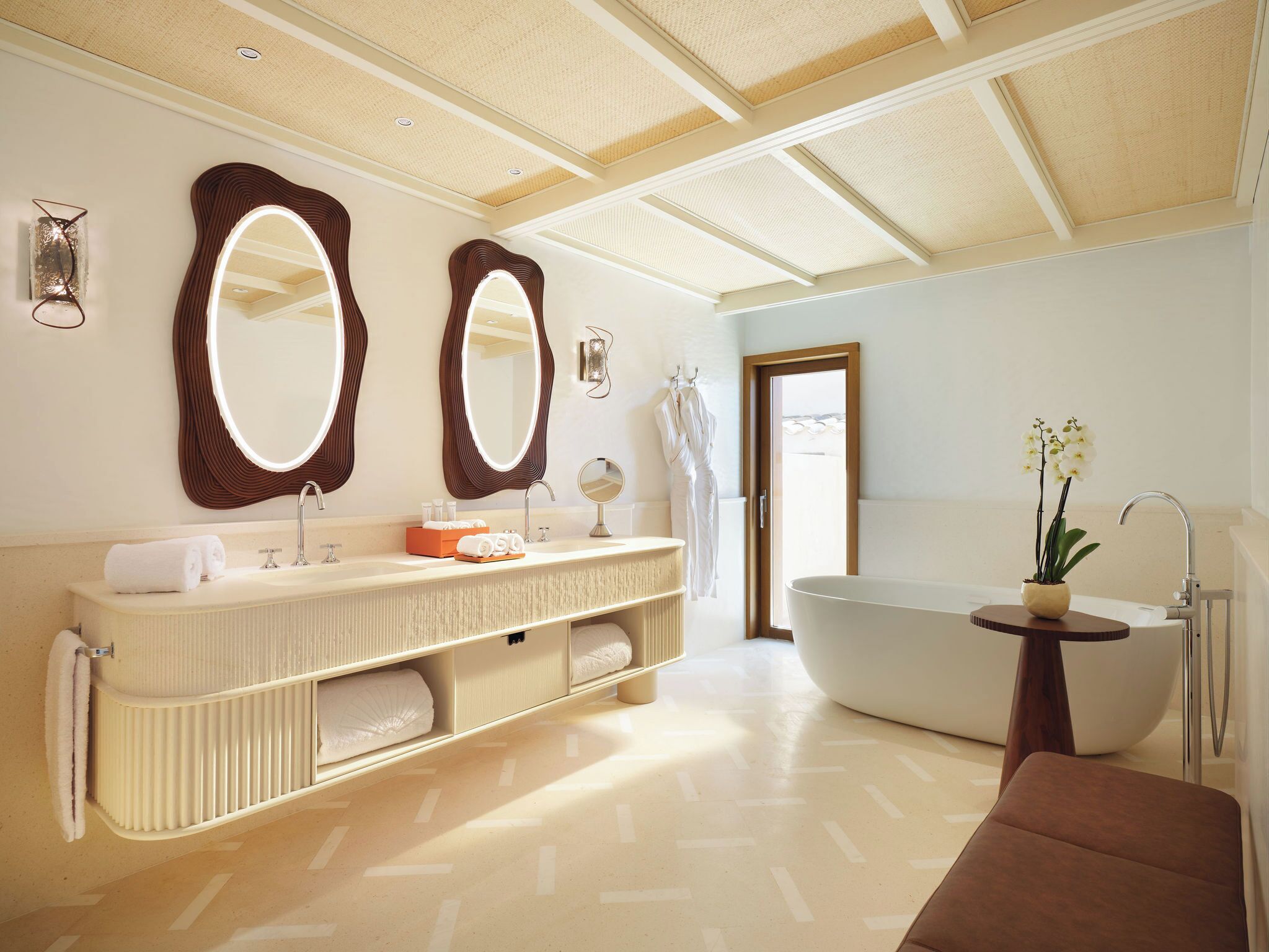 A modern bathroom with a freestanding bathtub, a large vanity with two mirrors, and a towel rack.
