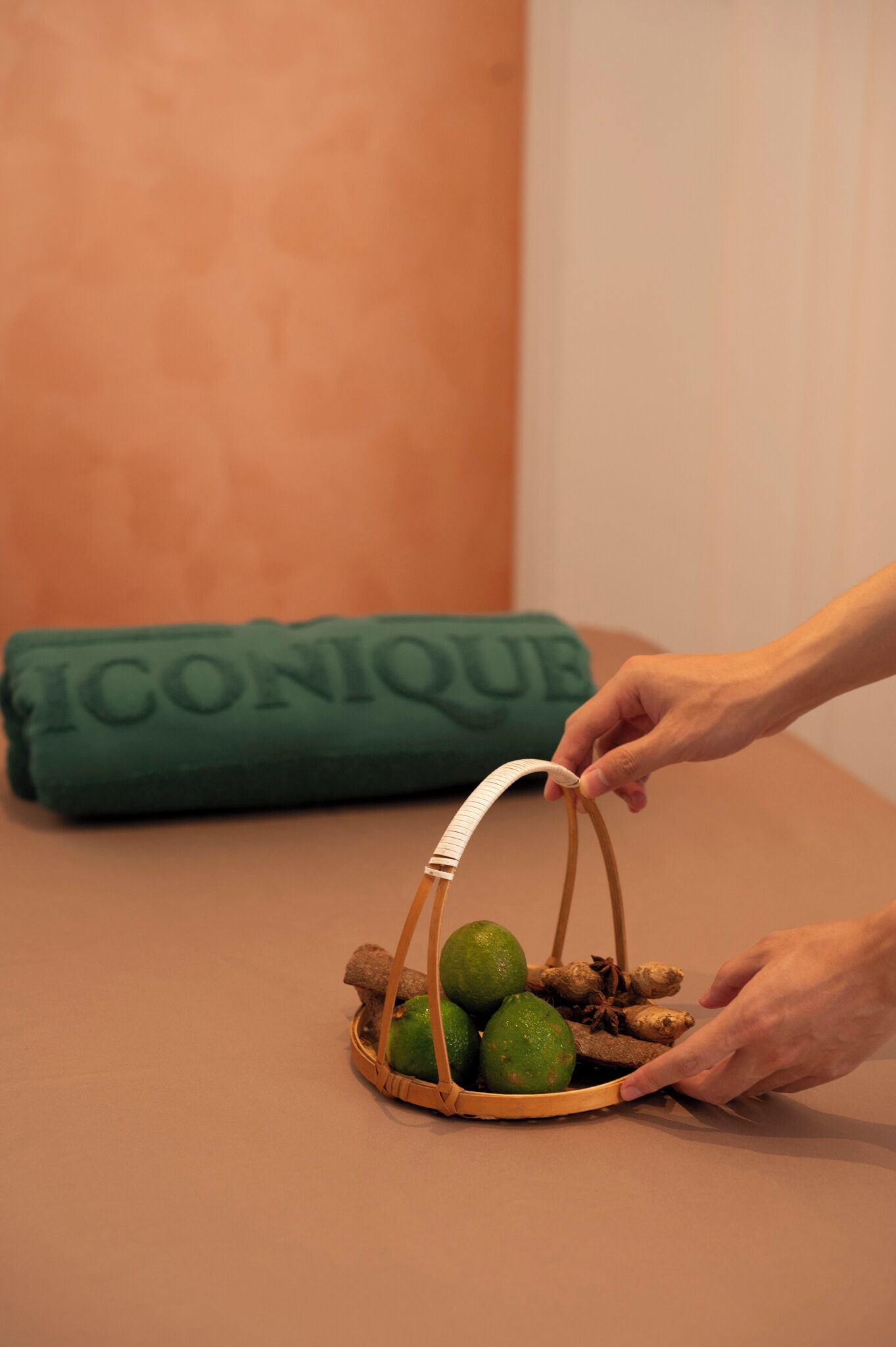 A hand placing a woven basket with lime and ginger on a table.