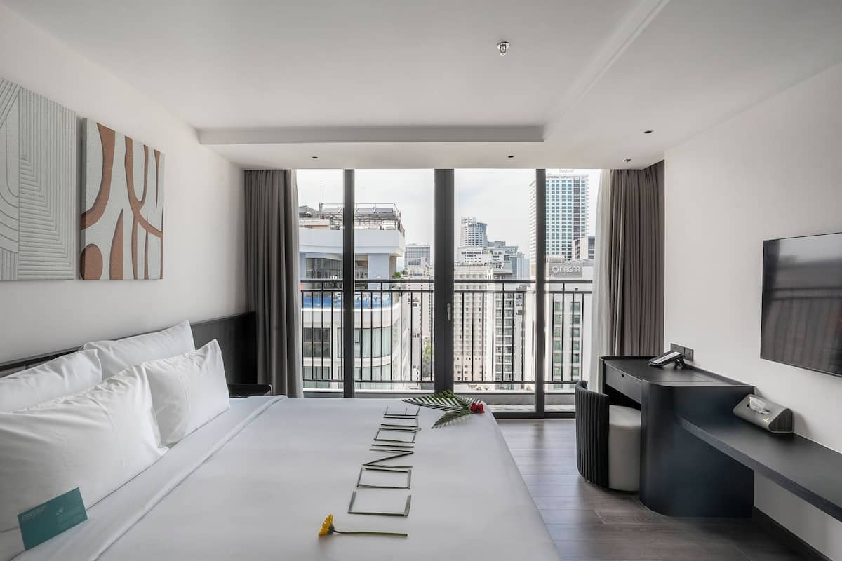 A modern hotel room with a large bed, a desk, and a TV.