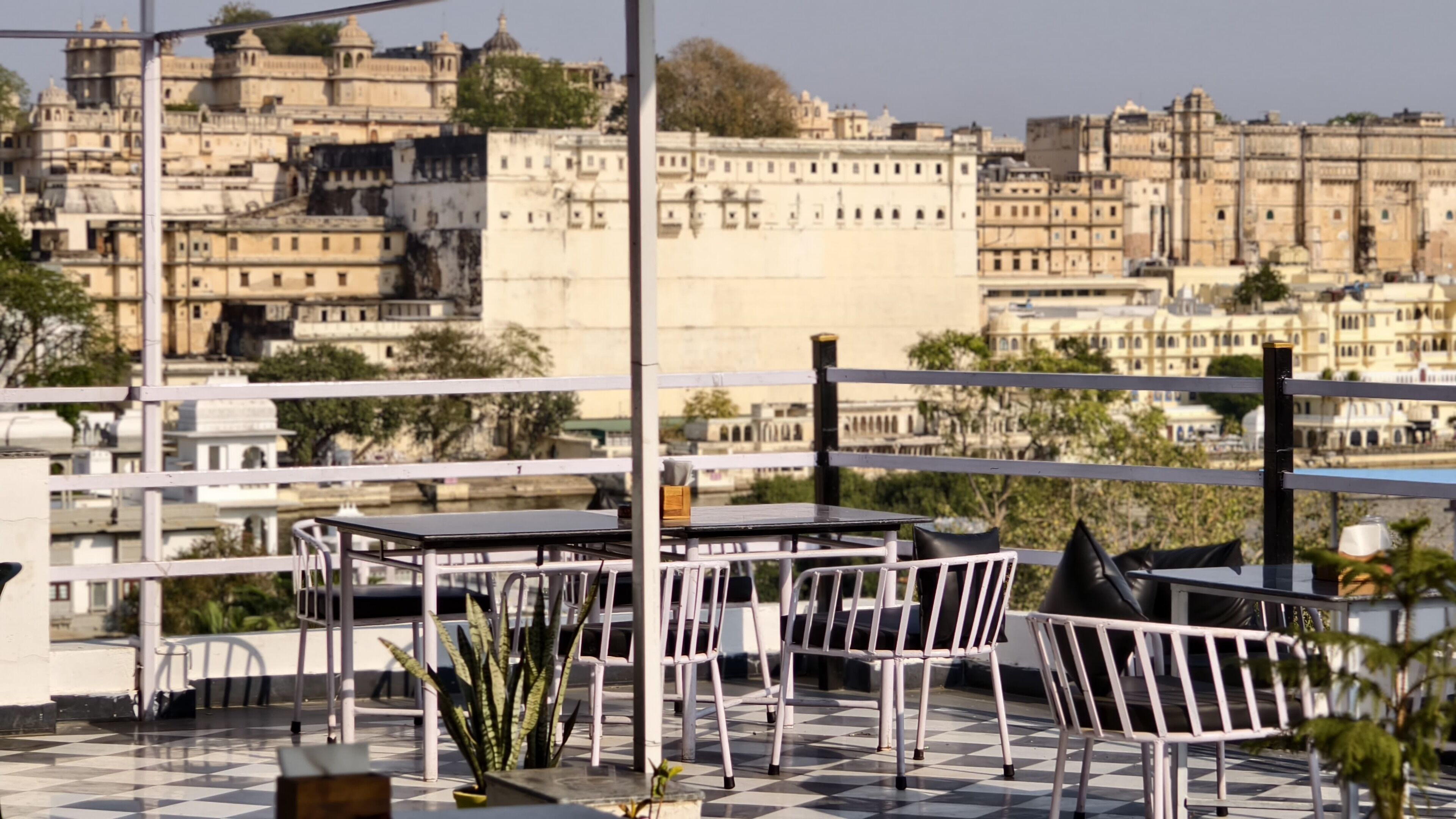 Eine Terrasse mit Tischen und Stühlen mit Blick auf eine historische Stadtlandschaft mit traditioneller Architektur.