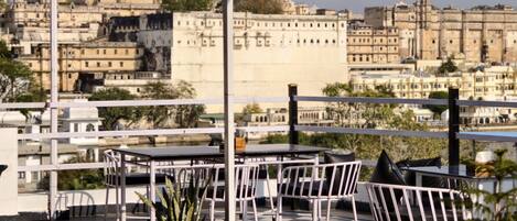 Eine Terrasse mit Tischen und Stühlen mit Blick auf eine historische Stadtlandschaft mit traditioneller Architektur.