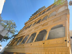 Un immeuble à plusieurs étages doté d’éléments architecturaux raffinés, notamment des balcons sculptés et des moulures décoratives.