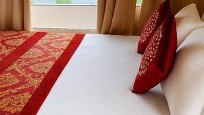 Quarto de hotel com uma cama grande, vista para a água e cortinas.