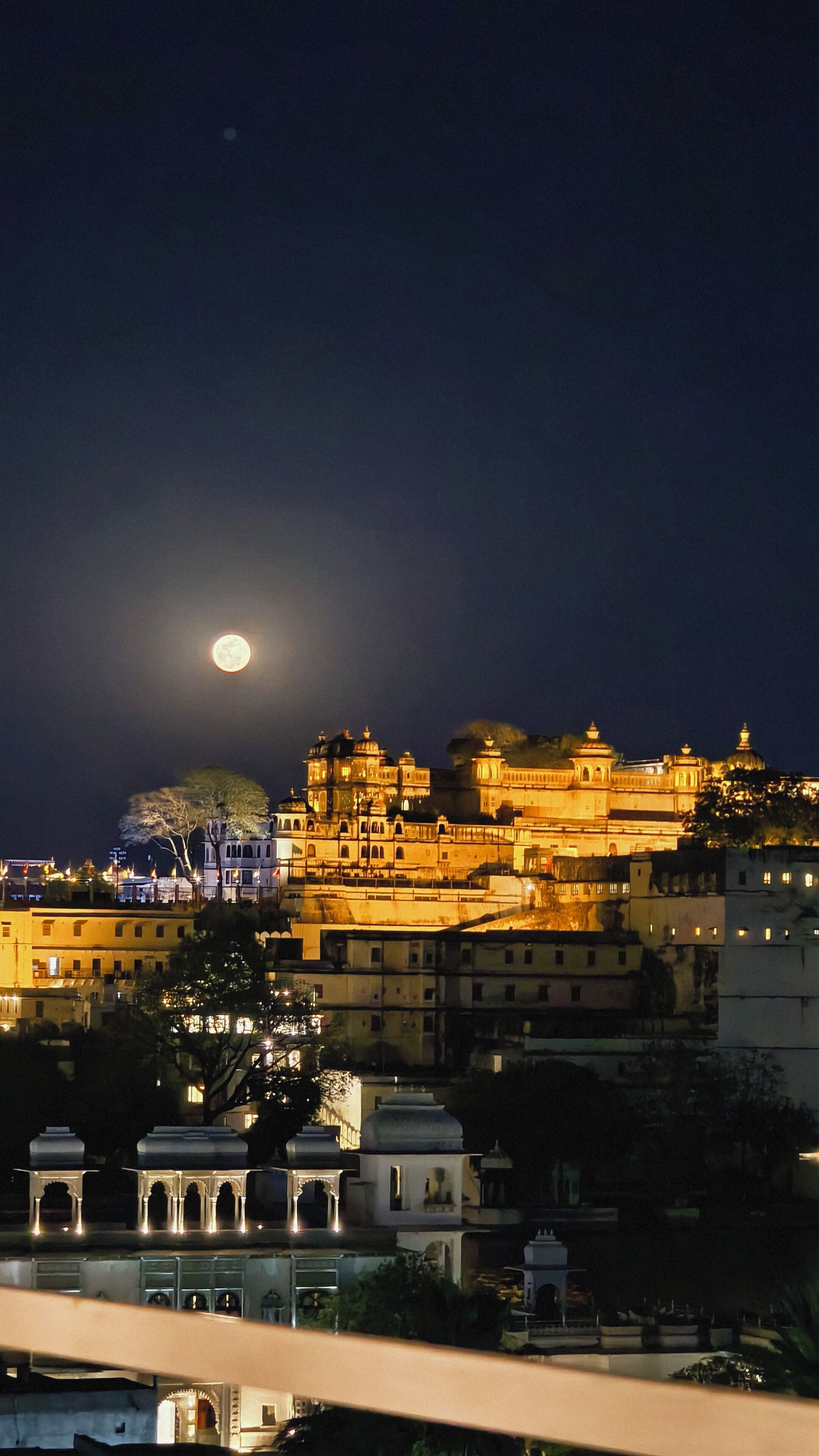 Un ensemble de bâtiments historiques à plusieurs niveaux, dotés de structures en forme de dôme, illuminés la nuit.
