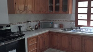 Una cocina con armarios de madera, microondas, tostadora, pileta y estufa.