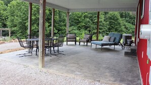 A covered patio with outdoor furniture, including a table and chairs, and a sofa. - Mammoth Cave Cabin Rentals 12 (Mammoth Cave)