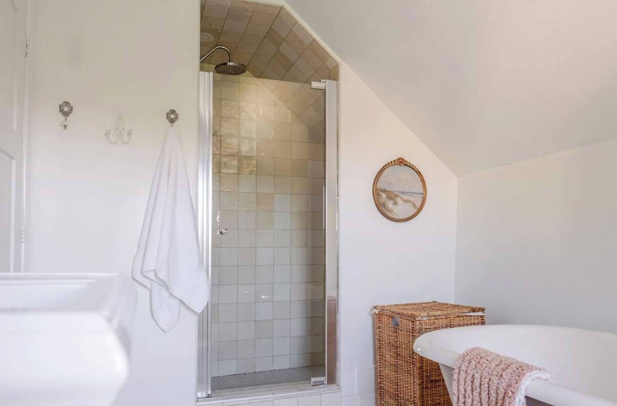 Un baño con ducha, bañera y una cesta de mimbre.