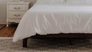 A bedroom with a bed, a nightstand, a wall hanging, and a ceiling light fixture.
