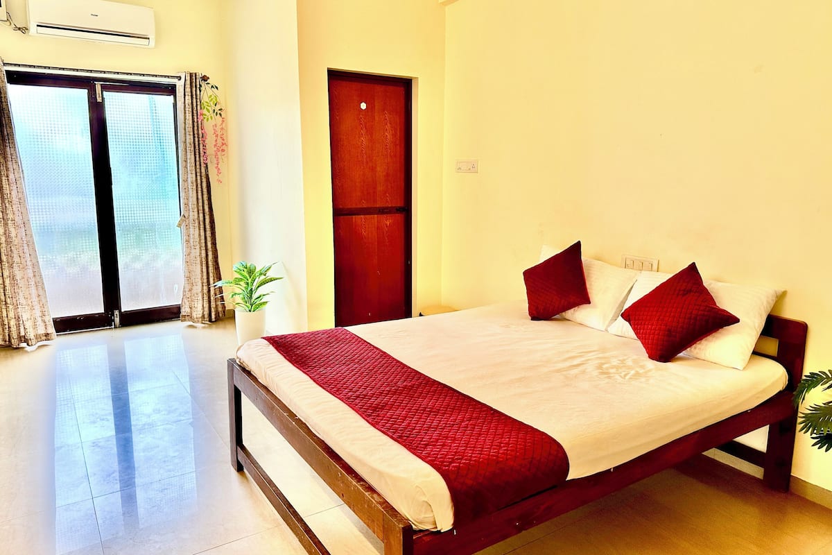 A hotel room with a bed, a potted plant, and a sliding door.