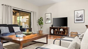 Una sala de estar moderna con un sofá, una mesa de centro, un televisor y elementos decorativos.