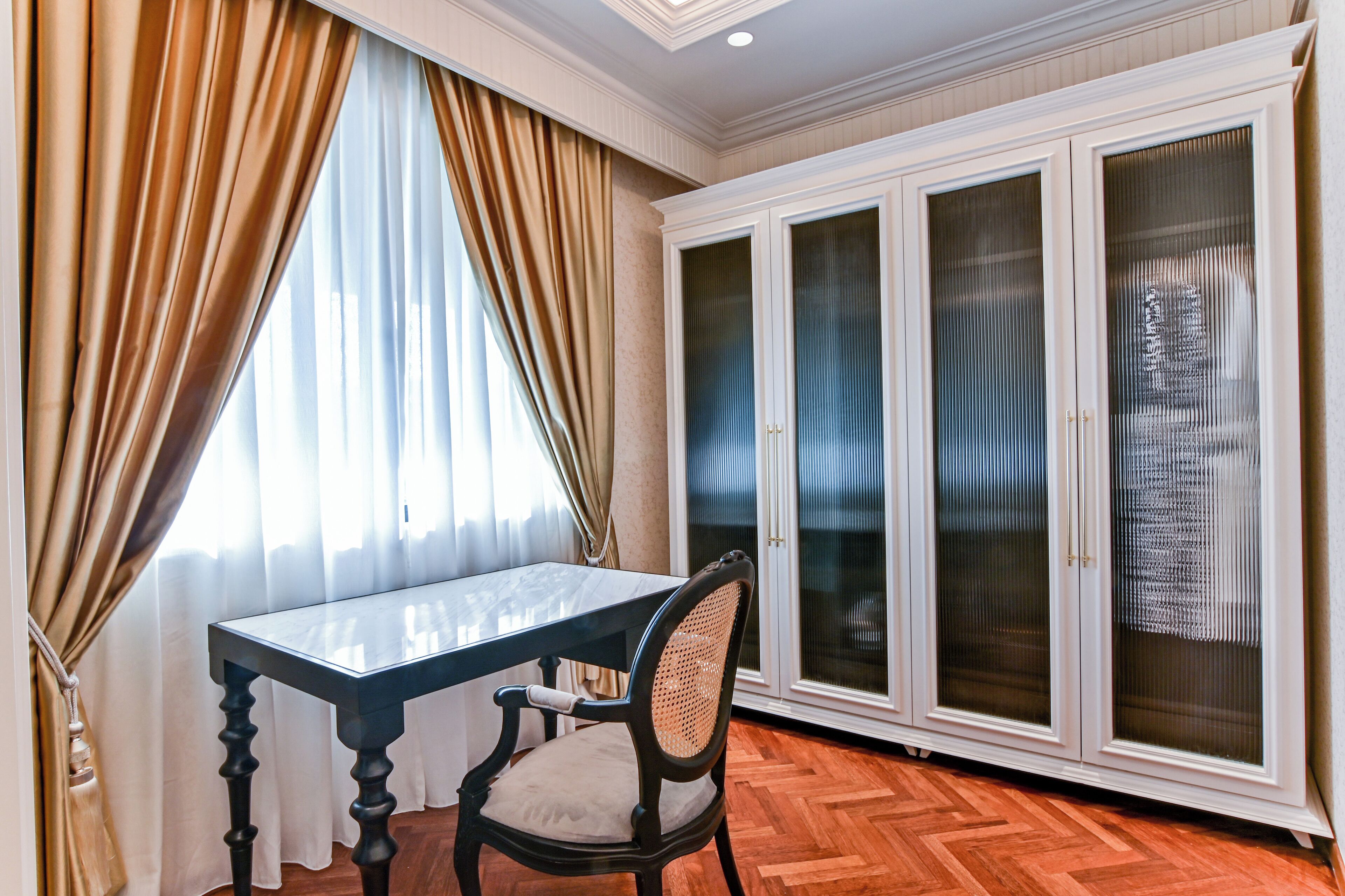 A room with a dining table, a chair, and a large cabinet with glass doors.