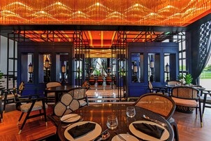 A restaurant with a modern interior, featuring wooden tables and chairs, and a decorative ceiling.