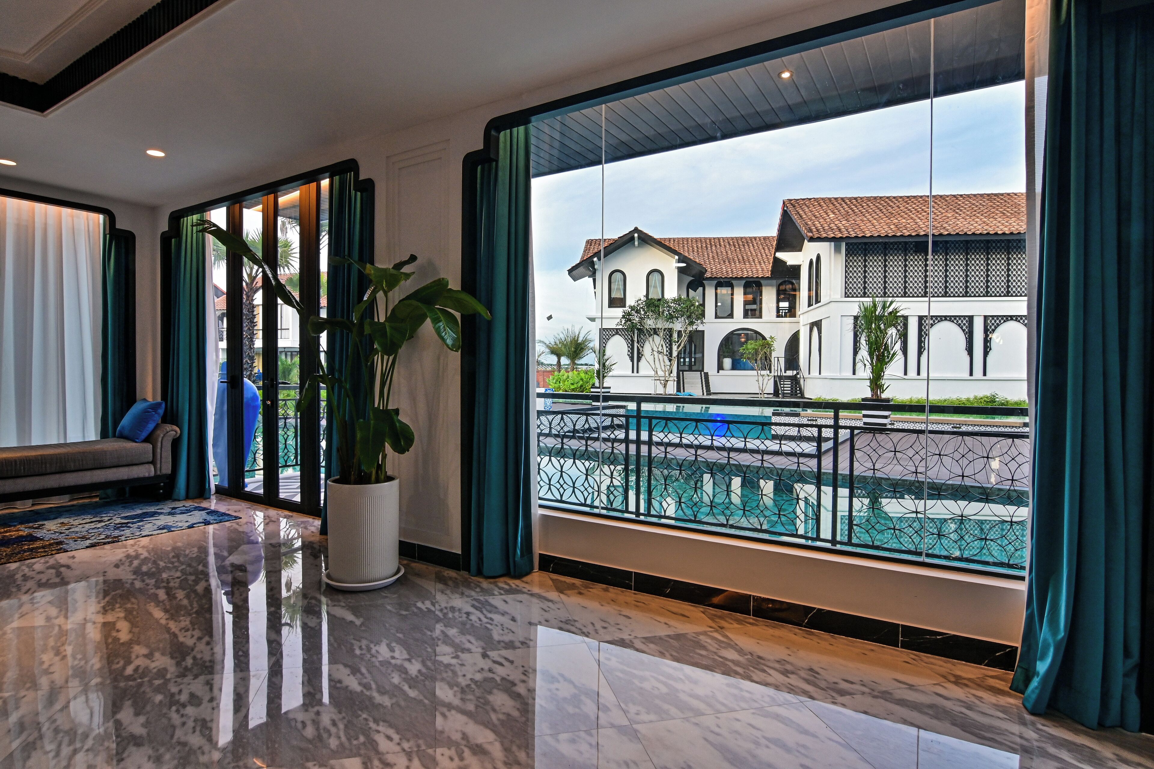 A spacious room with a large window, a potted plant, and a marble floor.