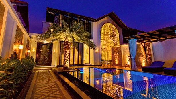 Un hotel moderno con piscina, un espacio exterior cubierto y una entrada bien iluminada.