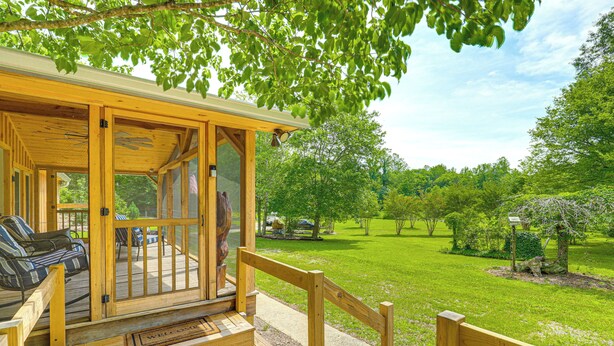 A wooden deck with a bench and a welcome mat, overlooking a well-maintained lawn and trees. - Serene Cabin w/ Pond & Creek on South Saluda River (Cleveland)