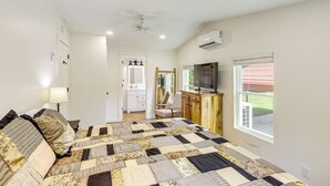 A bedroom with a large bed, a ceiling fan, a TV, and a window with blinds. - Serene Cabin w/ Pond & Creek on South Saluda River (Cleveland)