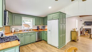 A spacious kitchen with green cabinets, a white refrigerator, and wooden countertops. - Serene Cabin w/ Pond & Creek on South Saluda River (Cleveland)