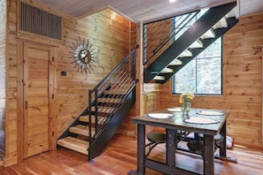 A wooden interior with a staircase, a dining table with chairs, and a window. - Cottage at Deer Ridge Farm (Charlottesville)