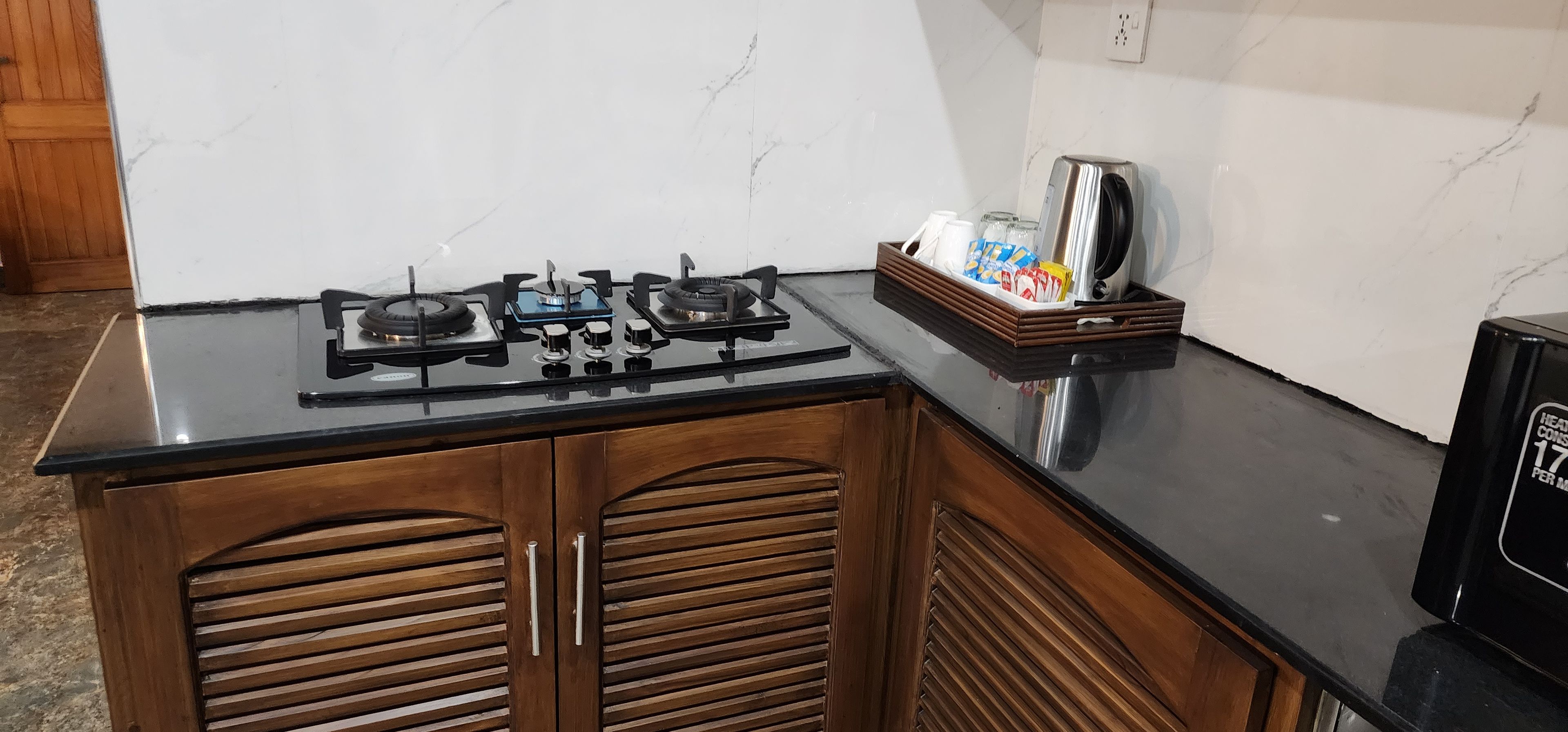A kitchen with a black countertop, a gas stove, wooden cabinets, and a coffee maker on the counter.