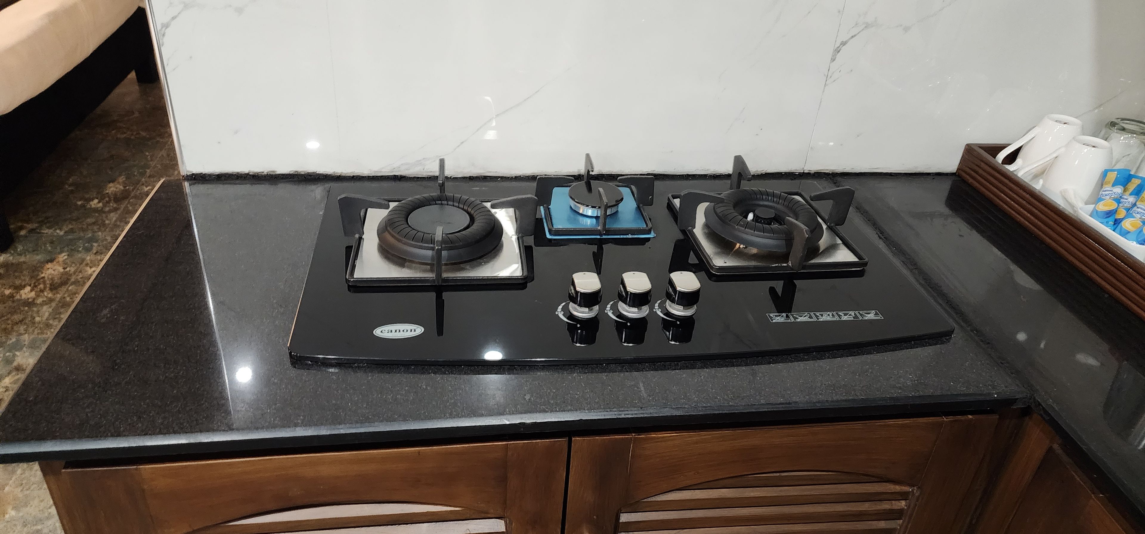 A kitchen with a black countertop, two gas stoves, and a range hood.