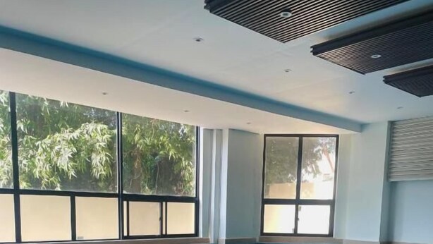 Una piscina interior con agua azul cristalina, grandes ventanales y suelo de baldosas.