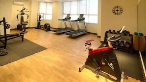 Un gimnasio amplio con cintas de correr, máquinas de pesas y un muro de espejos.