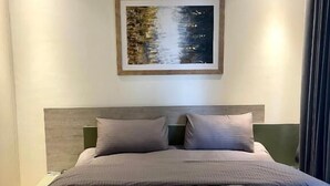 Una habitación de hotel moderna con una cama grande, un cabecero y una obra de arte enmarcada en la pared.