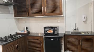 A kitchen with wooden cabinets, a black refrigerator, a microwave, and a gas stove.