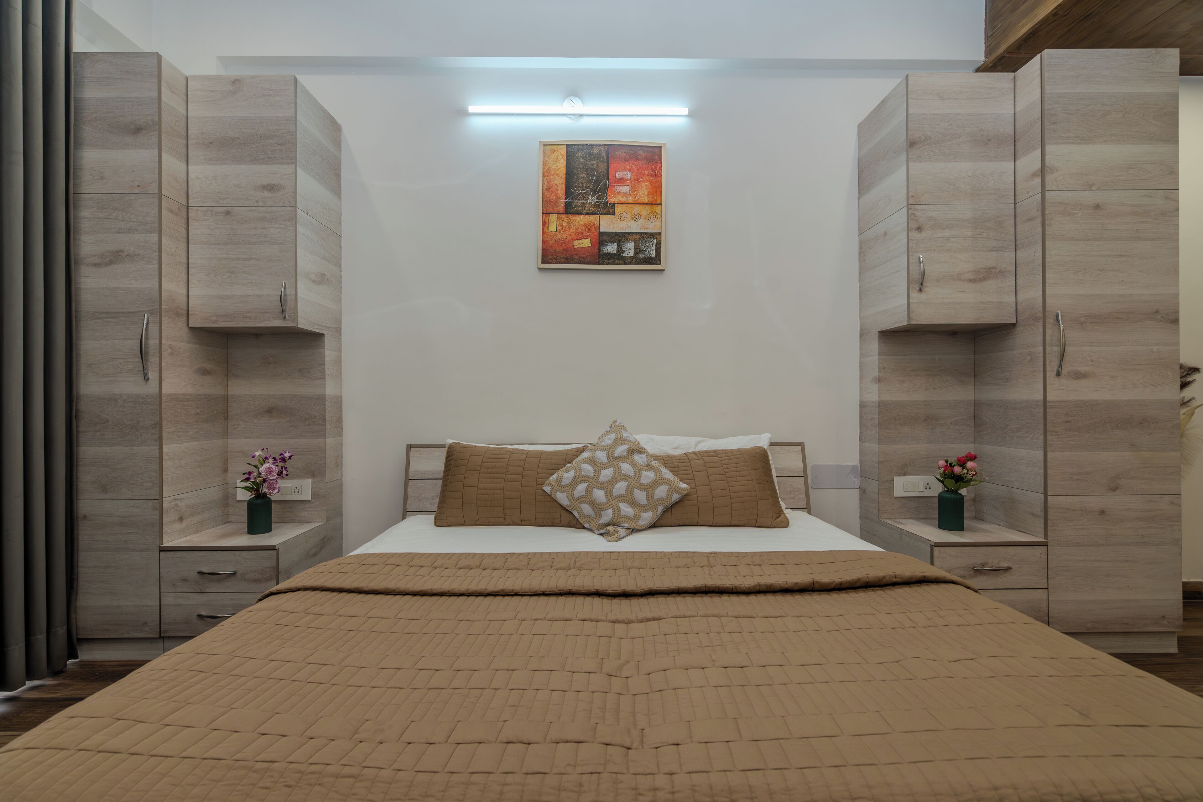 Un dormitorio con cama, armario de madera, mesitas de noche y una obra de arte colgada en la pared.