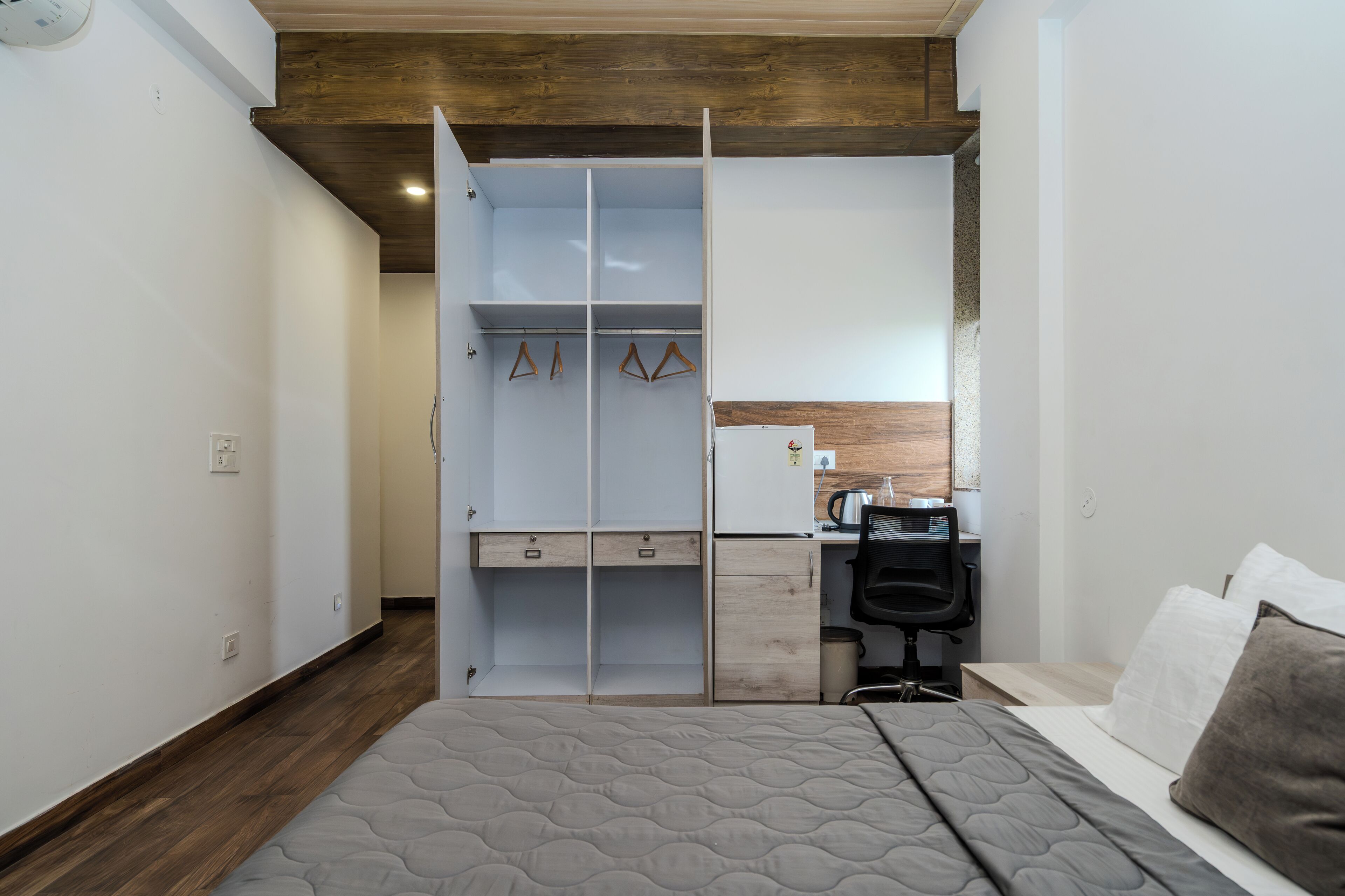 A bedroom with a bed, a desk, a chair, and a wardrobe.