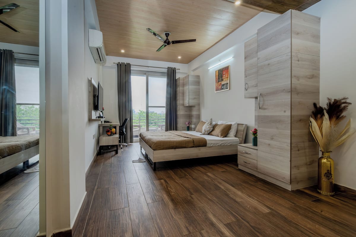 A modern bedroom with a bed, a wardrobe, a TV, and a view of the outdoors.