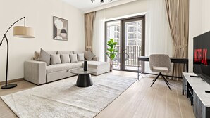 A modern living room with a sofa, coffee table, and a TV. - Lotus at Creek Beach 1 - 407 2BD (Dubai)