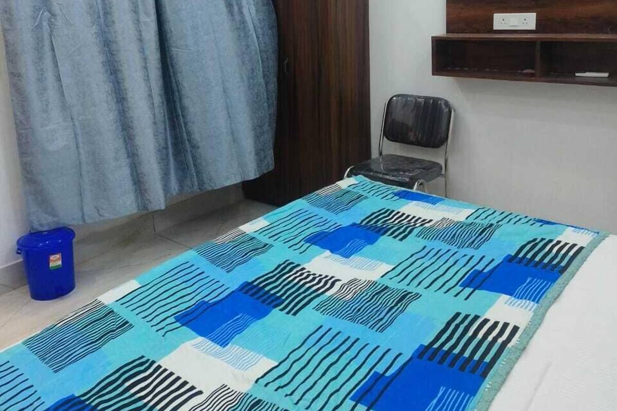 Ein Schlafzimmer mit einem Bett, einem Schrank, einem Stuhl und einem blauen Eimer.